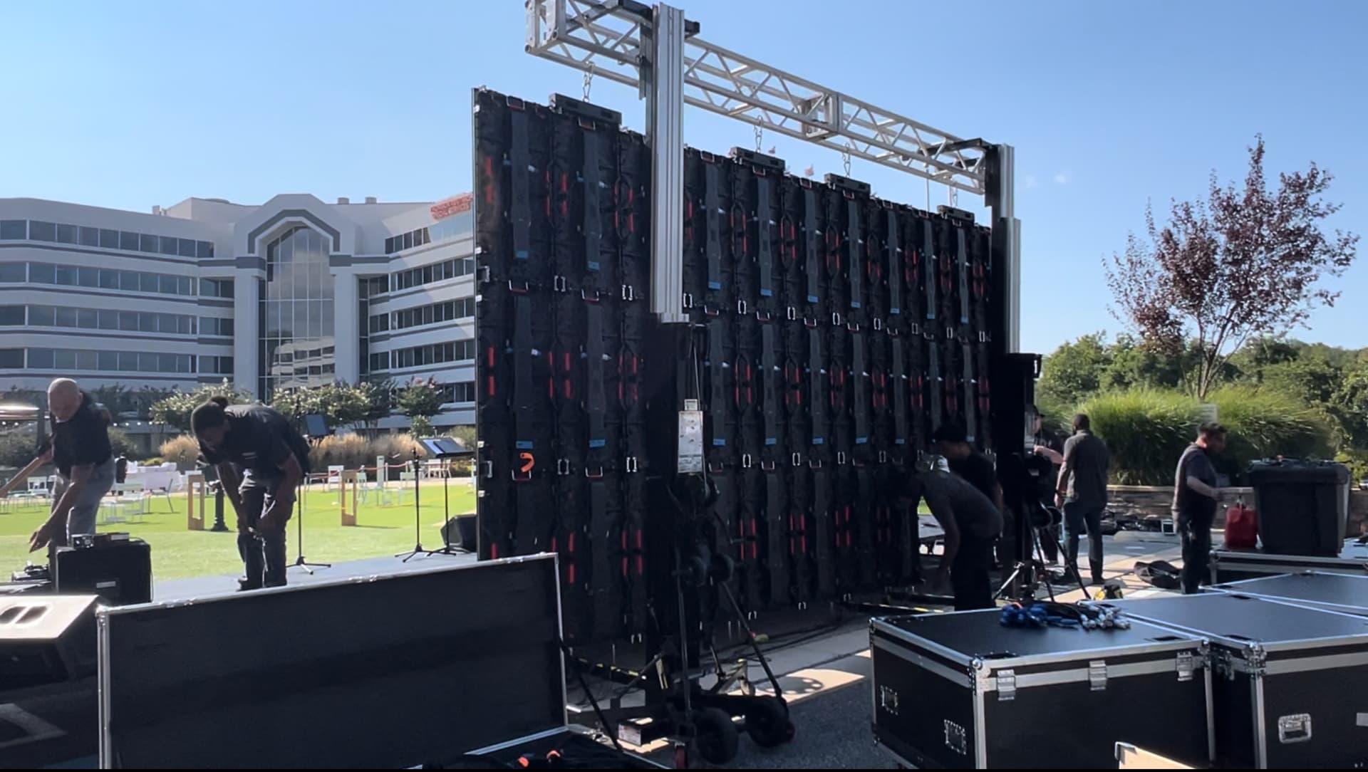Crew building an outdoor LED video wall on ground support truss beside road cases