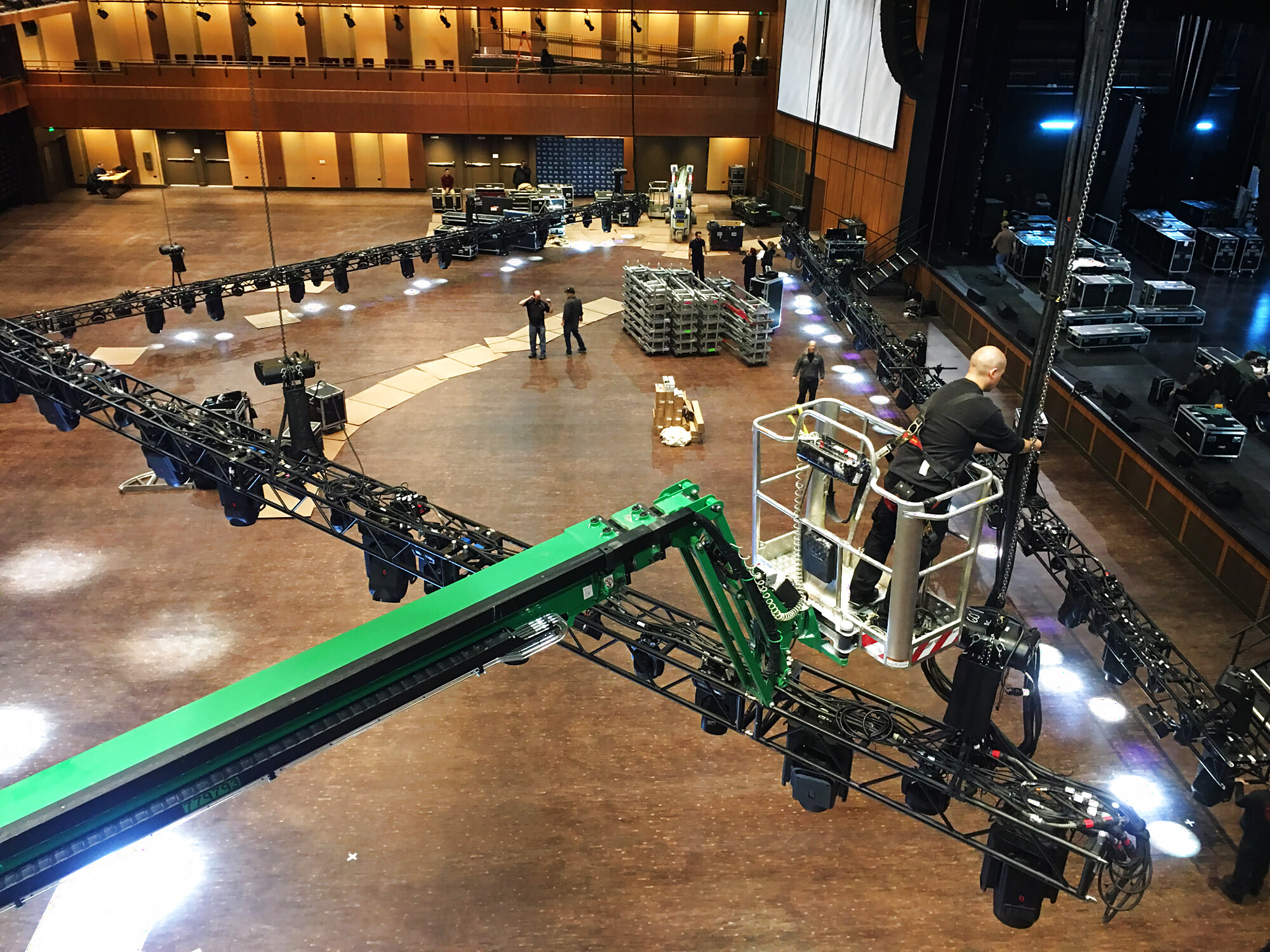Crew rigging lighting truss from a boom lift inside a performing arts hall